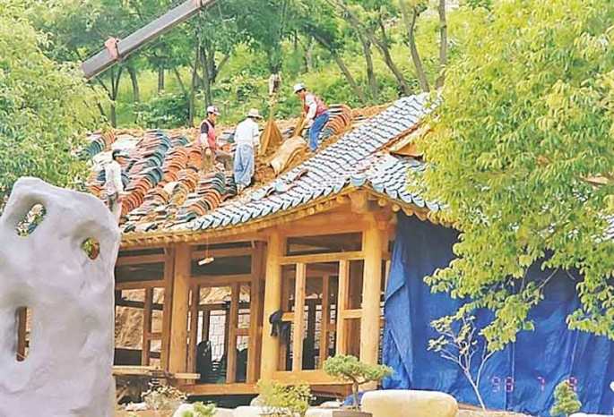 People working on the constructing the traditional Korean blue-tiled roof house in Wolmyeongdong